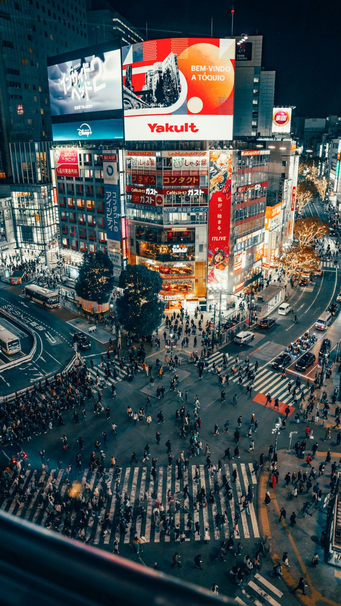 gallery-5 A bustling night scene of Shibuya Crossing, Tokyo, with vibrant city lights and crowds.