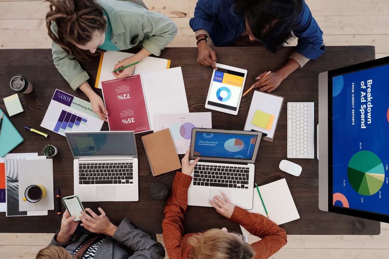 contact-img A diverse team collaborating on digital marketing strategies at a desk, using laptops and tablets.